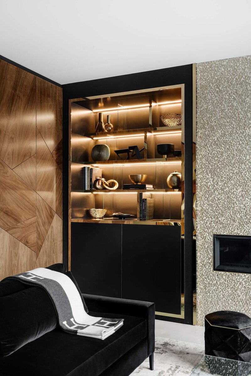 A built in shelf with walnut, brass and black and gold metallic accent tile.