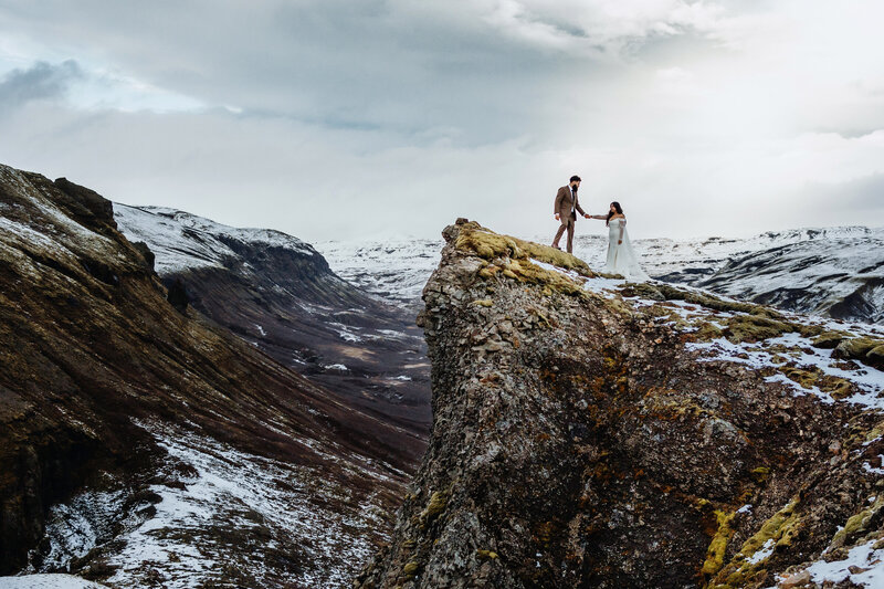 married couple is walking on a lava field in the Icelandic highlands during sunset hours