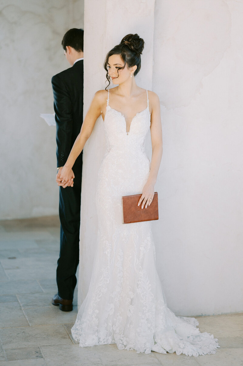 bride holding a grooms hand as he reads vows during wedding day first touch at villa antonia, austin wedding venue