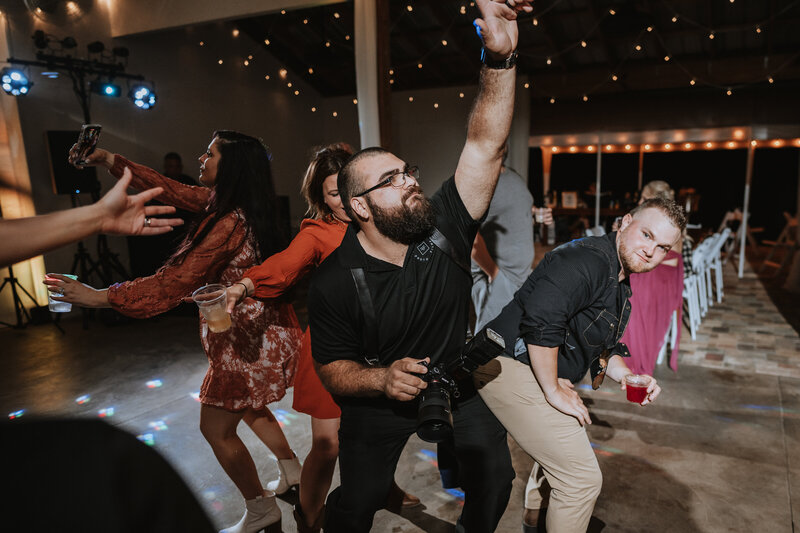 photographer dancing with wedding guests on the dance floor