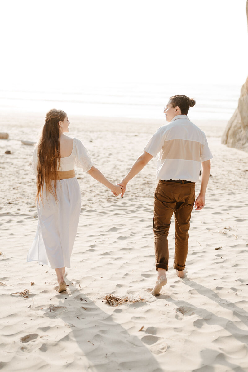 a couple holding hands while walking on the beach
