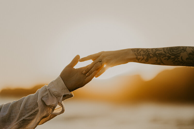 Deux mains s’effleurant au coucher du soleil, capturées par Laura, photographe couple en Vendée.