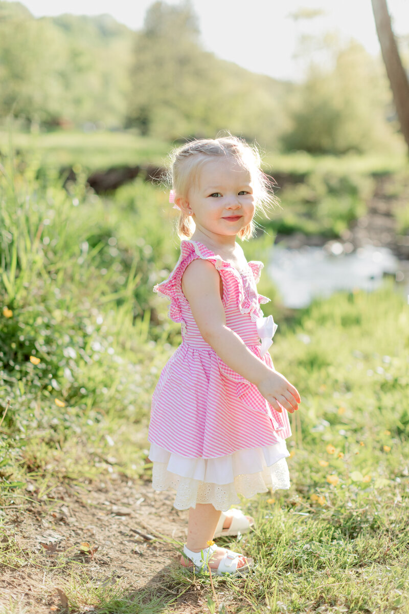 young girl smiling outside wearing a pink dress