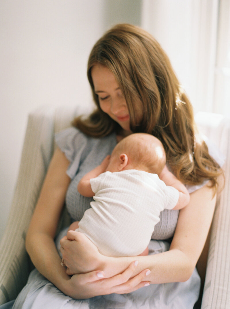 Mom holding newborn while sitting, newborn is sleeping