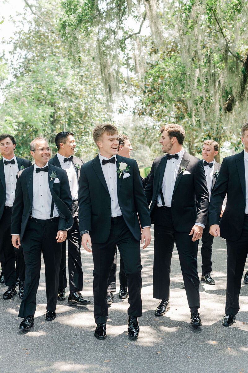 Groom walking towards camera with groomsmen