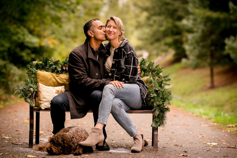 Parents kissing during a family photoshoot in Seattle's Eastside, with their bored, cute little puppy.