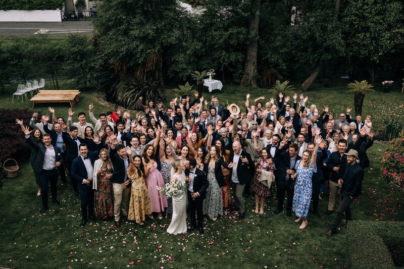 a group photo of 100 wedding guests on a manicured lawn in merivale christchurch