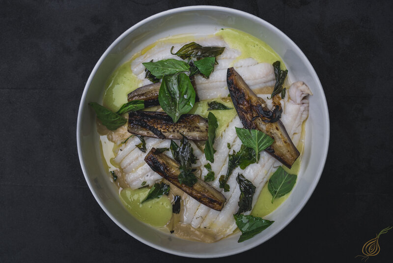 A white bowl filled with a colorful assortment of fish and fresh vegetables, elegantly presented for a healthy meal.