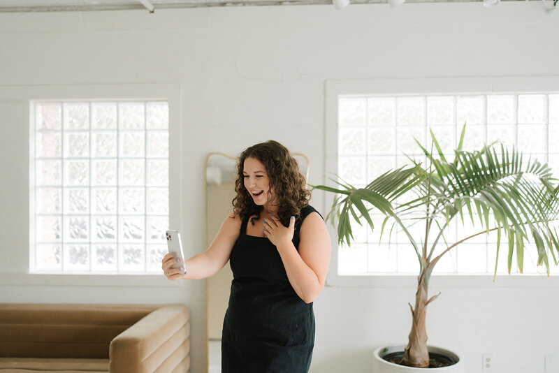 Morgan carrying a laptop and coffee cup by a table