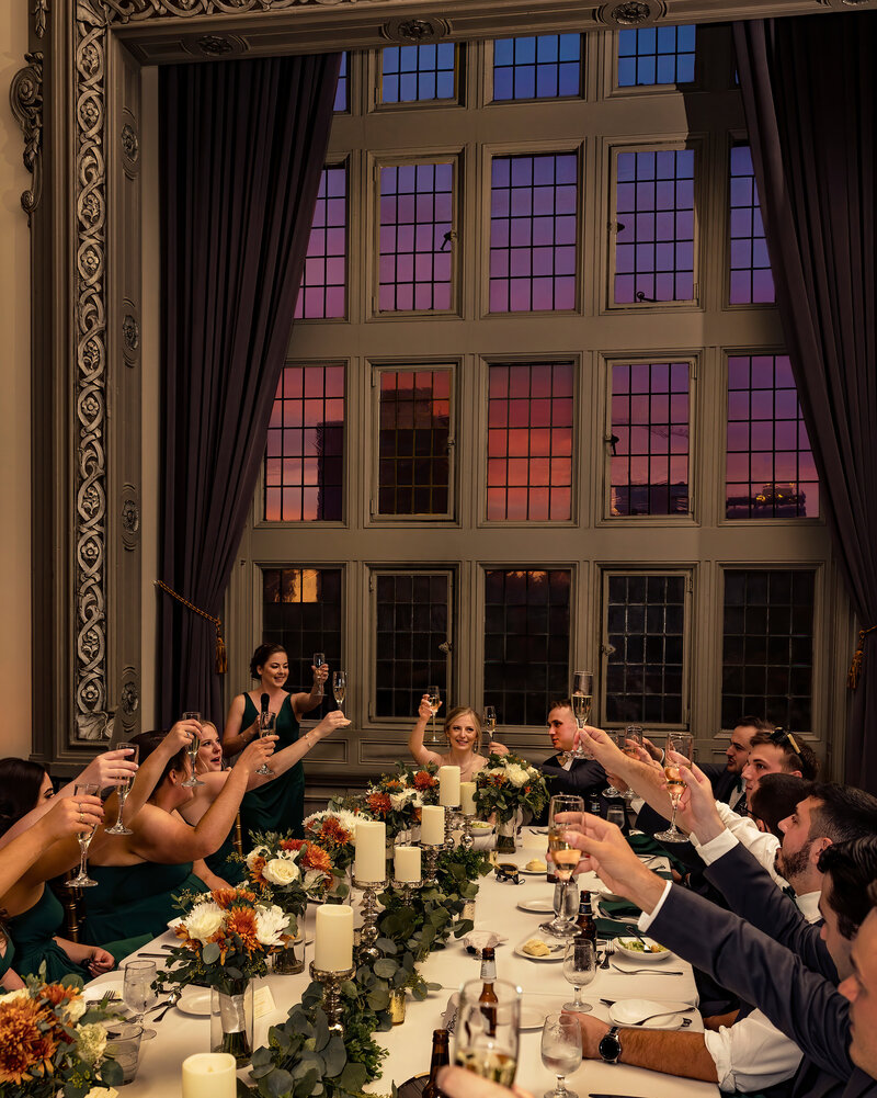 As the sun sets at Tudor Arms the couple and bridal party offer up a toast with their glasses in the air.
