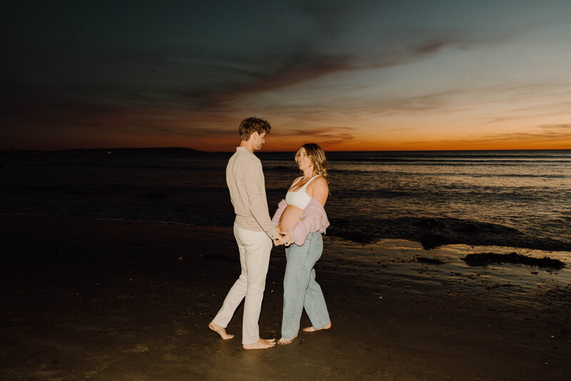 a pregnant woman and a man by the ocean