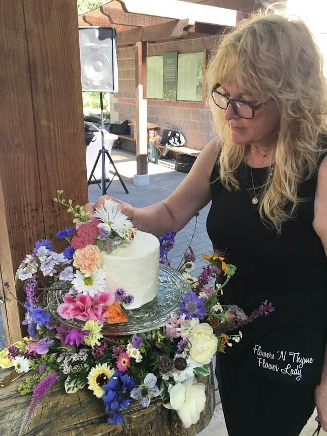 DelJean, a florist in Eugene, Oregon, places flowers on a wedding cake.