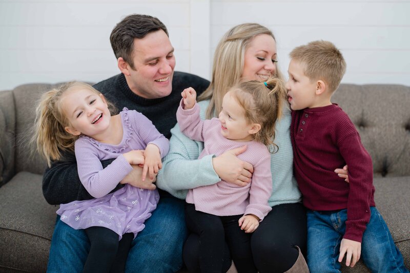 Couple walking through a mountain meadow with the Flatirons in Boulder, Colorado behind them, holding hands and laughing.
