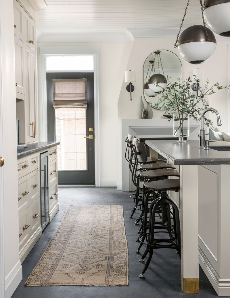 timeless black white and cream kitchen with industrial stools vintage rugs and timeless light fixtures