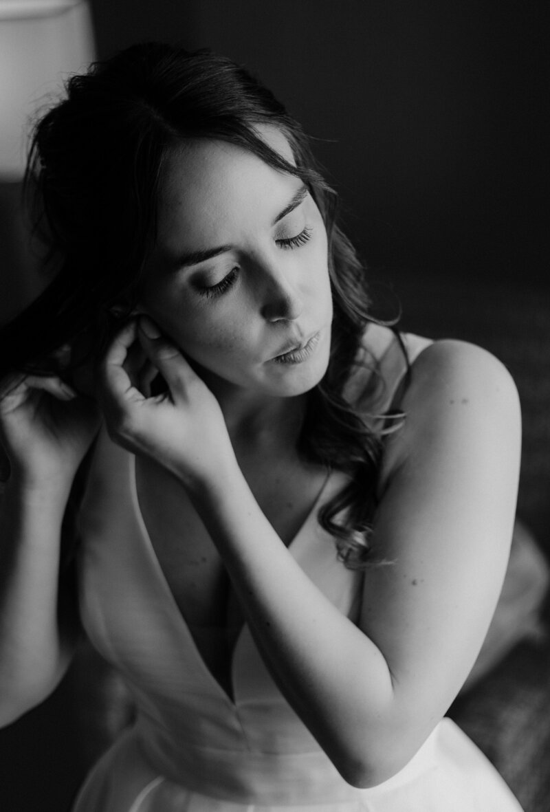 Bride puts her earrings on as she prepares for her wedding day.