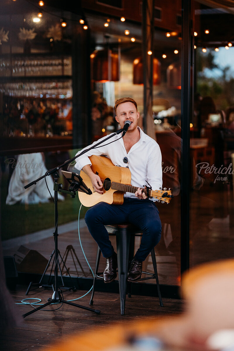 Ryan David Music playing guitar while singing at a wedding held at Petrichor Farm, near Canberra ACT. Photo by Acacia & Grace Photography