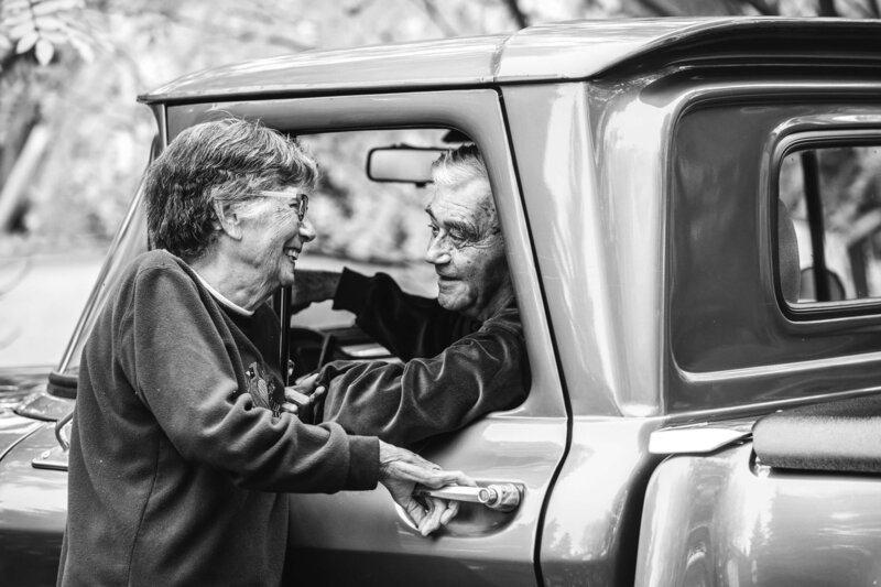 elderly couple smiles at each other in vintage truck