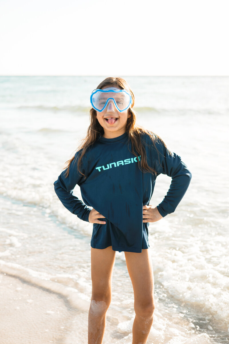 Model wears swim goggles while posing for camera in rash guard