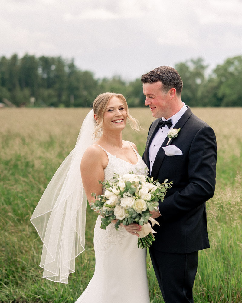 Bride and groom sit on a green couch for a portrait at their Elkins Estate Wedding.