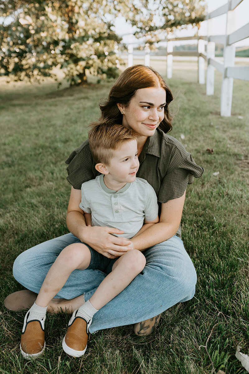 A mom and son sit in the grass with during a family photography session in Lafayette, Indiana.