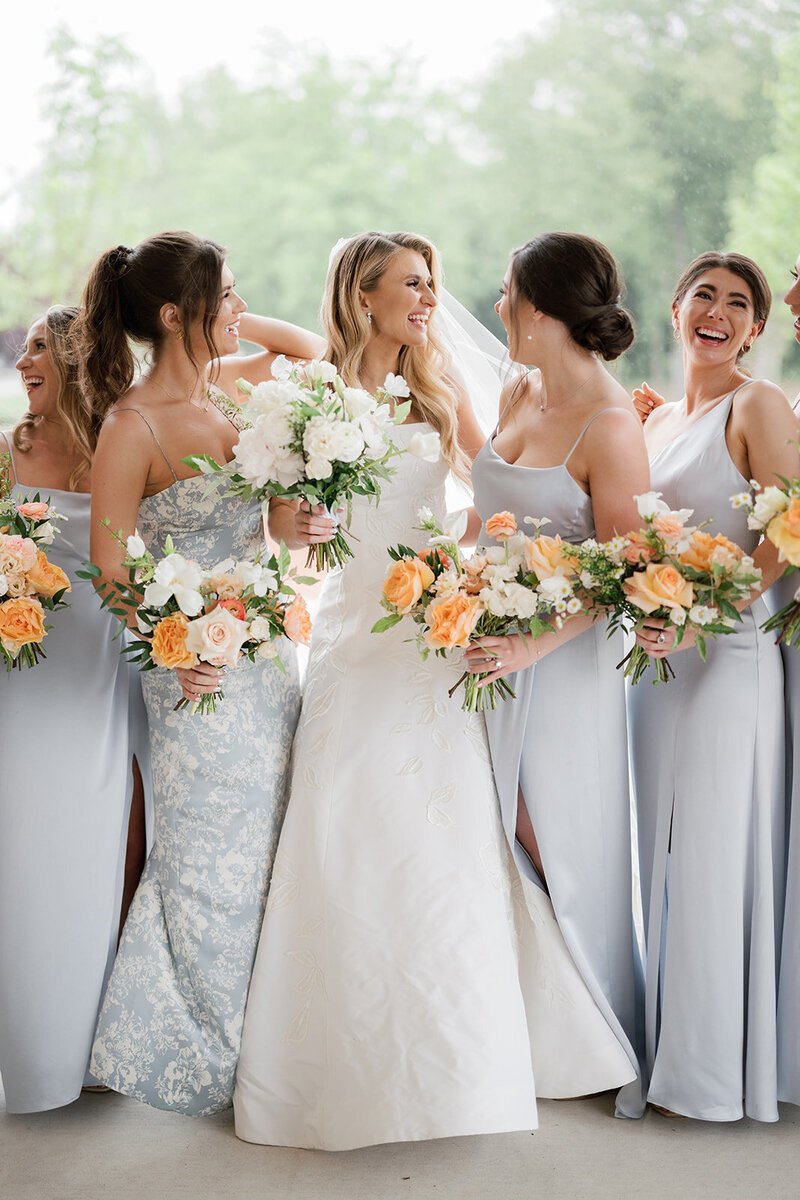 Bride and Bridesmaids smiling together while carrying bouquets