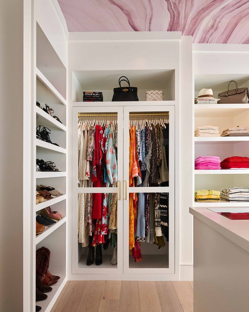 Women's walk-in closet with glass doors and open shelving