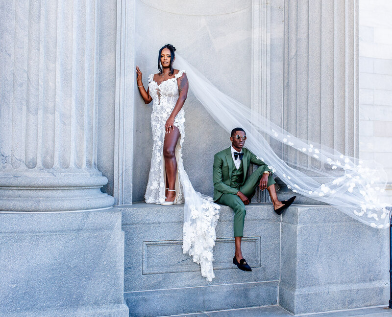 Capture the essence of Black luxury with this stunning image of a stylish couple at the SC Statehouse. The bride’s veil flows gracefully as the groom stuns in a green suit, set against a marble backdrop.