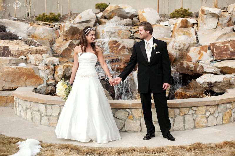 Winter wedding portrait of Bride and Groom in front of Stone Waterfall feature in the backyard of Cielo at Castle Pines