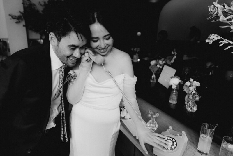 a bride and groom listen to an old phone
