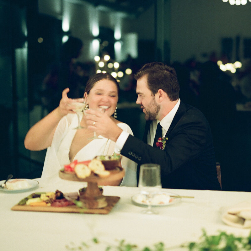 Couple cheers at wedding dinner