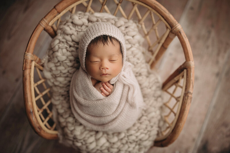 New Haven Newborn Photographer  captures adorable newborn baby girl wrapped in swaddle inside a wicker prop