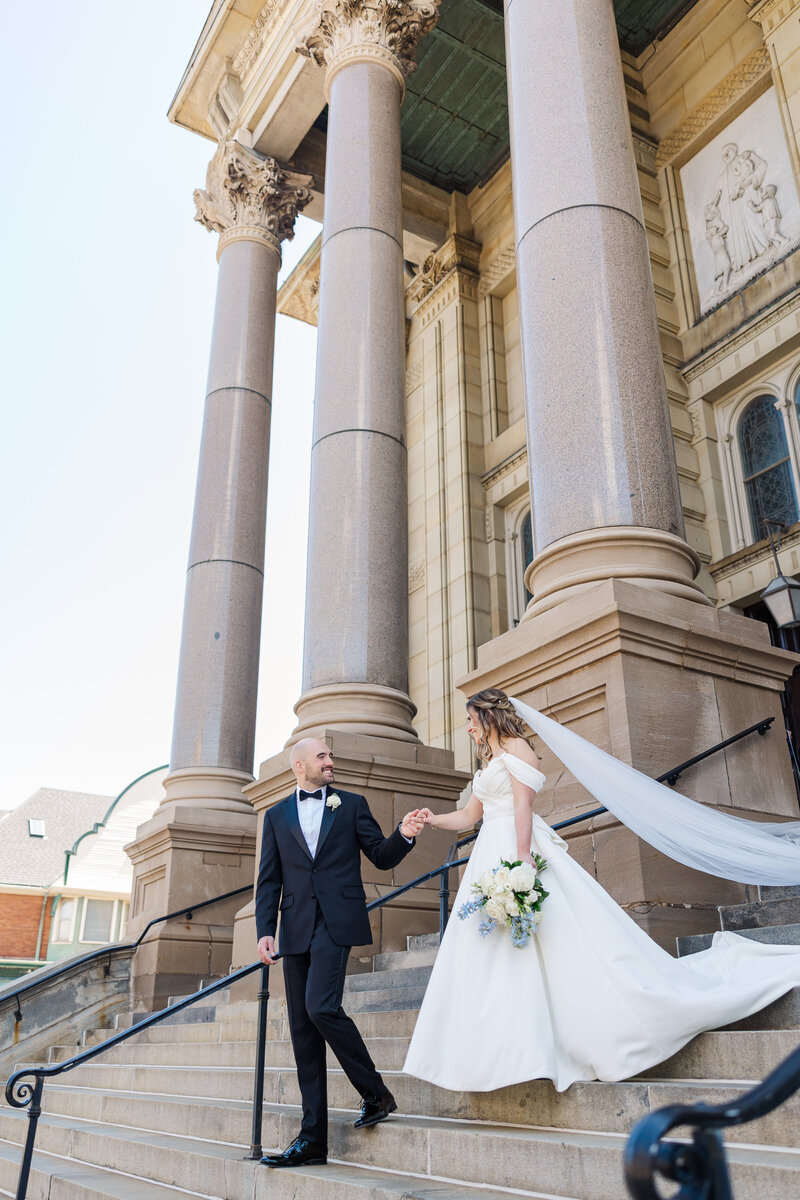 bride and groom holding hands outside of a grand building