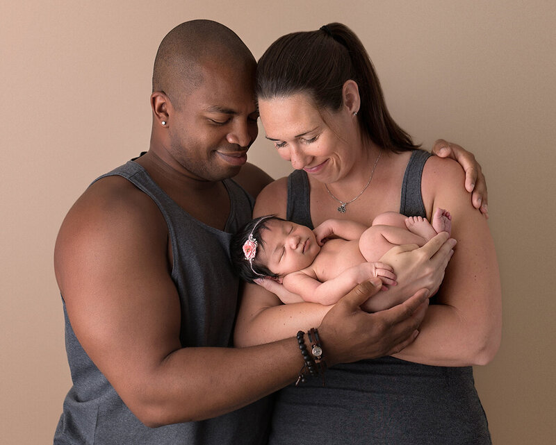 Family portrait of fit couple with their beautiful newborn baby girl.