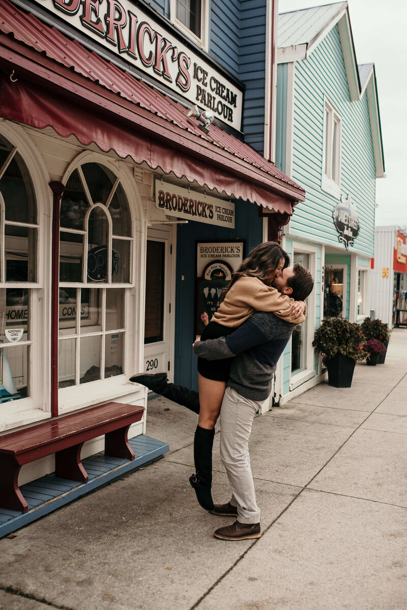 Man and woman share a kiss in front of an ice cream parlour