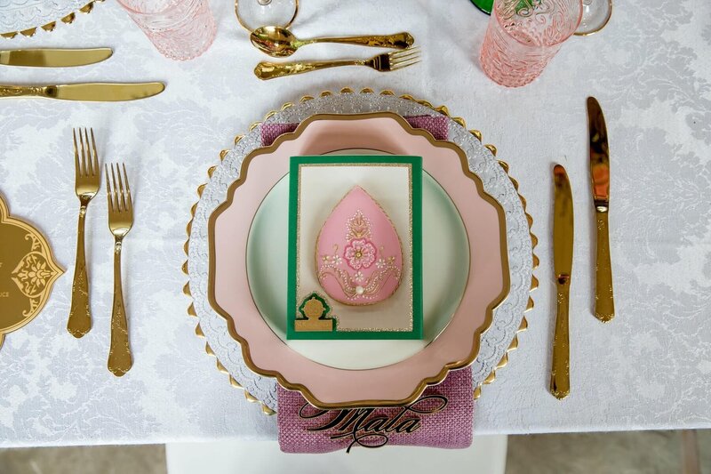 Elegant gold table setting with charger plate, personalised acrylic place name, gold cutlery and a beautifully decorated cookie