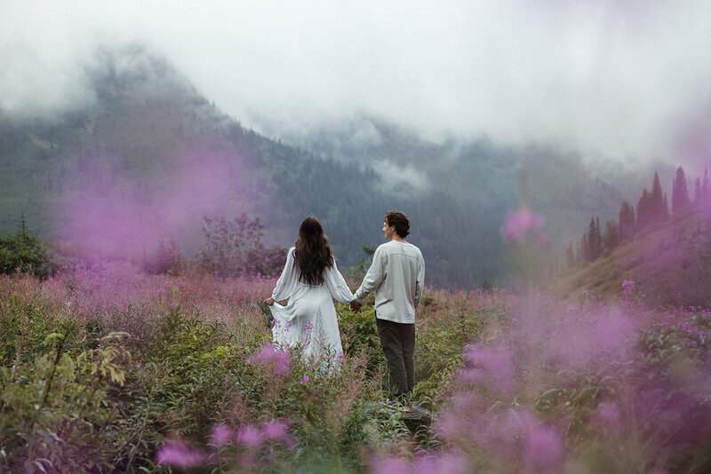 couple standing in field with purple wildflowers framing them
