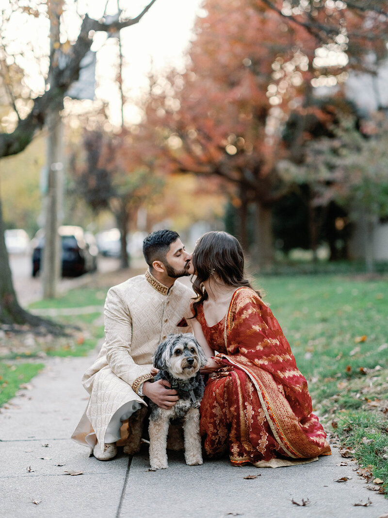 couple shares a kiss in front of their pup