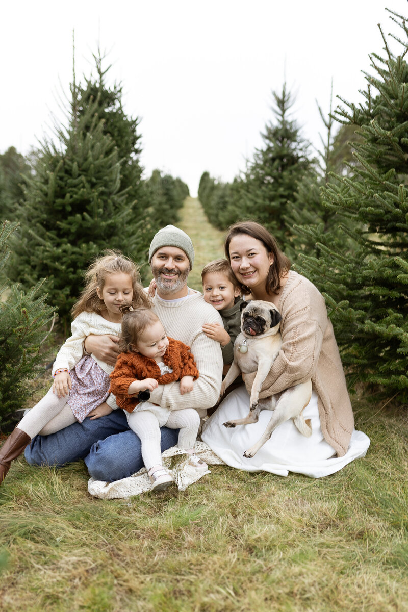 Smiling father holding two young children in fall outfits during an outdoor family photo session  in Maple Grove, Minnesota