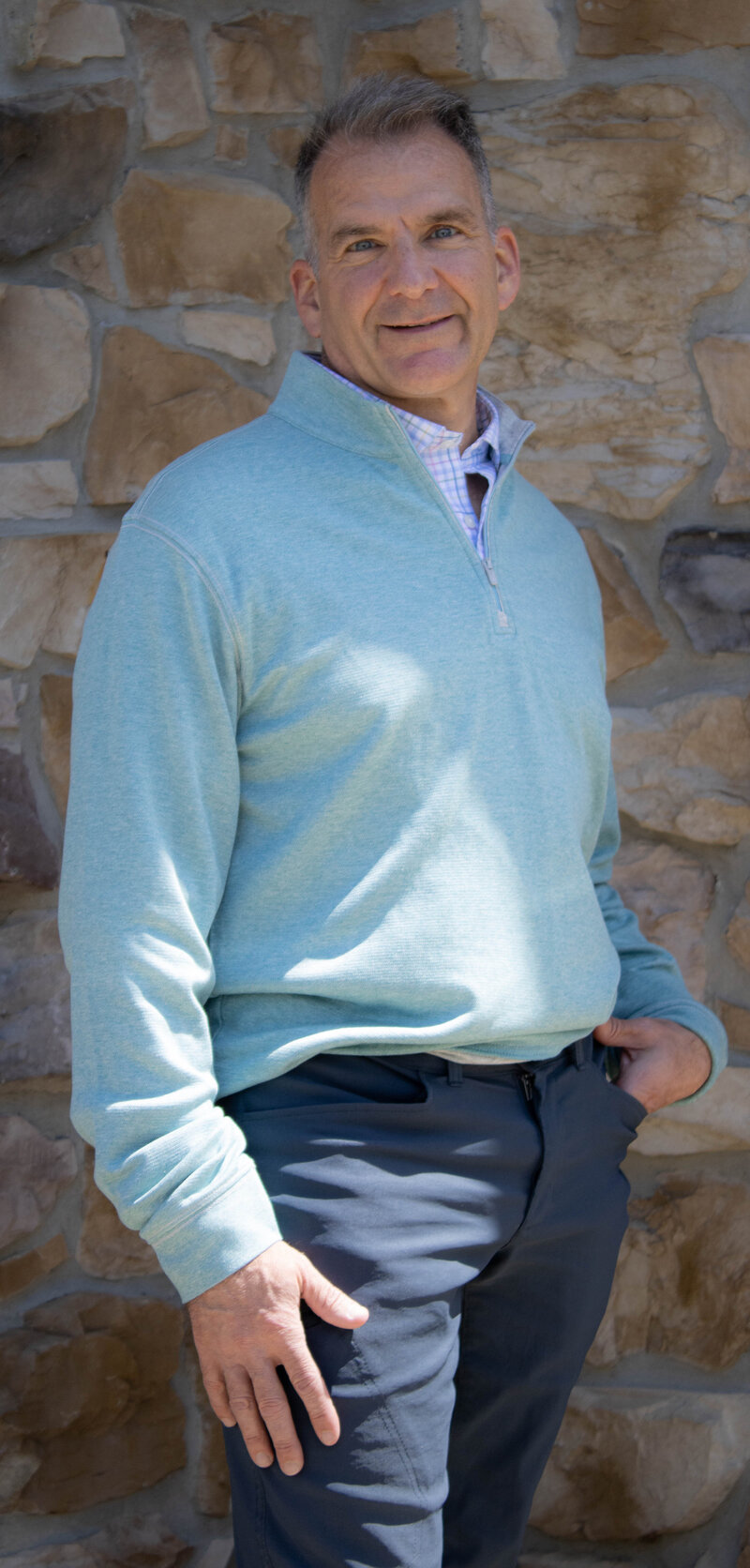 Dr. Leardi posing for a headshot behind a rustic stone wall. 
