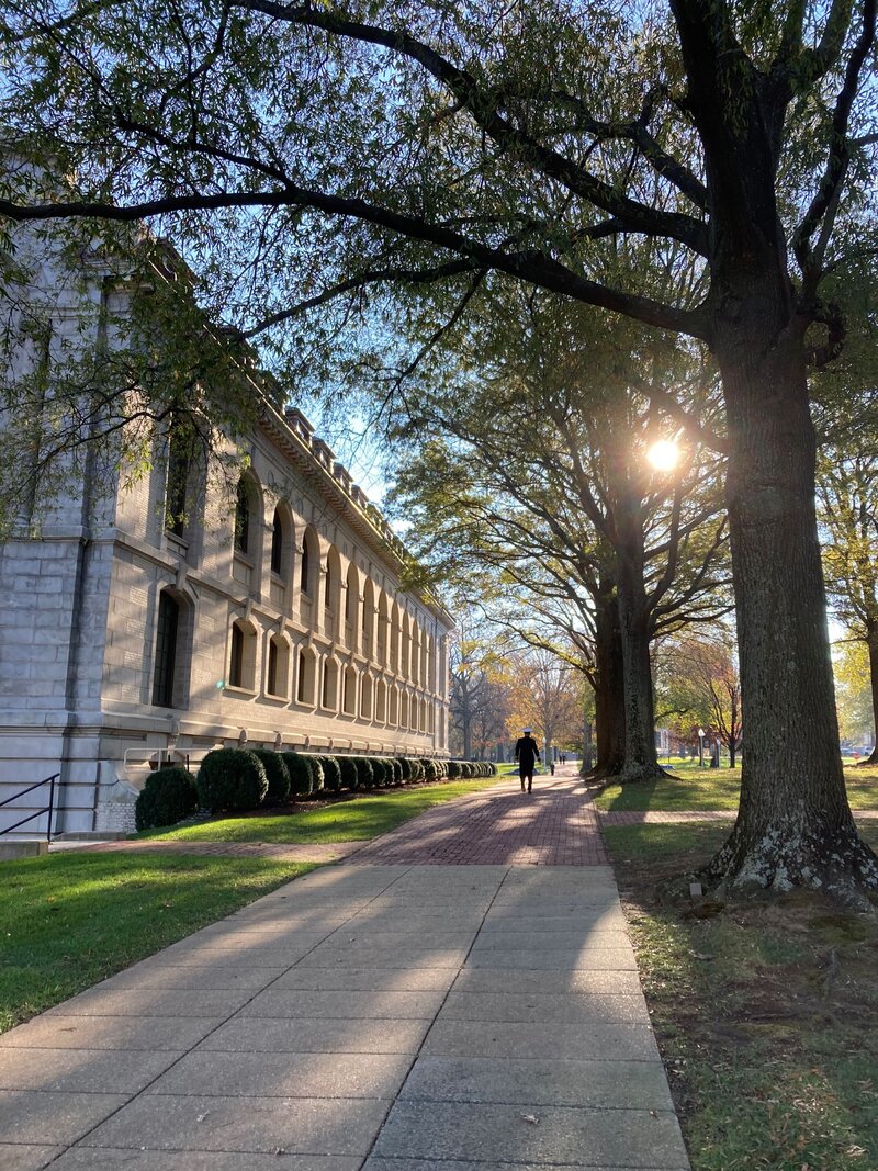 A midshipman walks down a brick walk at US Naval Academy.