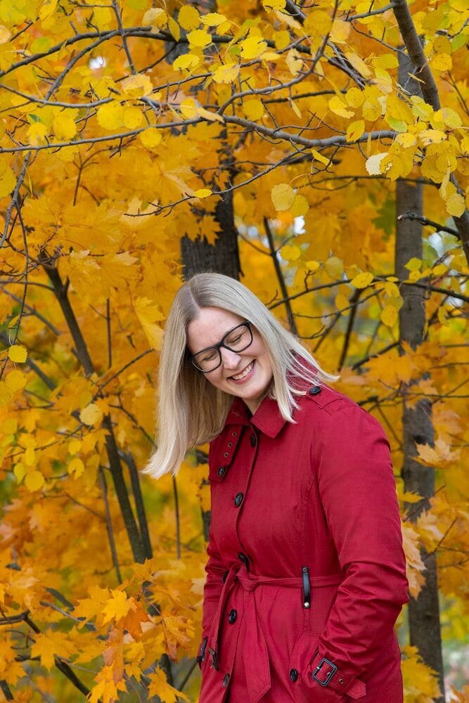 Jenny Moran enjoying a serene fall day surrounded by vibrant autumn foliage.

