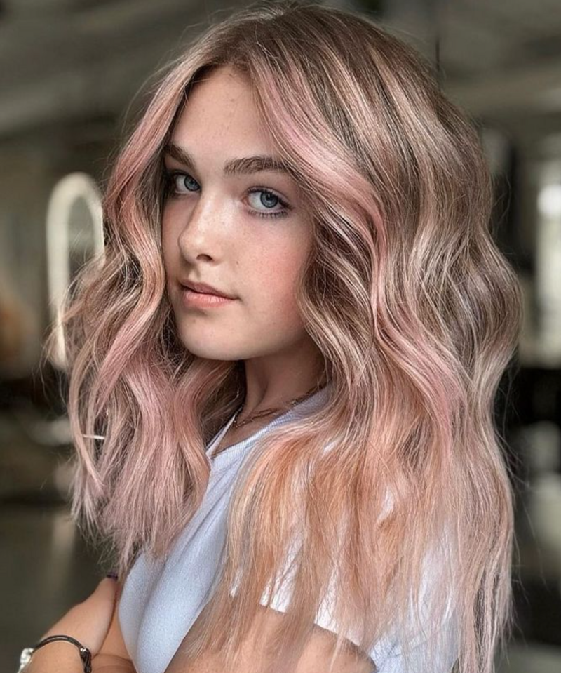 Young woman with soft, pastel pink balayage waves styled by Salon Beau.