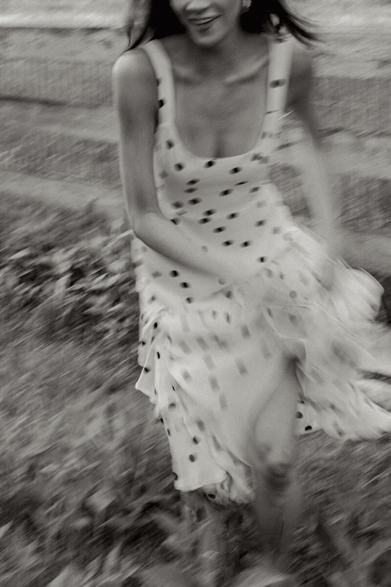 Black and white motion blur of a woman running in a flowy dress through tall grass. Editorial and emotive Greenville SC branding photograph by Dani Lacey Photographs.