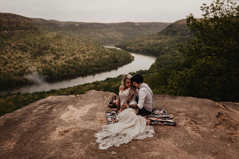 LGBTQ wedding couple sitting on edge of cliff in their adventure elopement at Snoopers Rock in Chattanooga, Tennessee