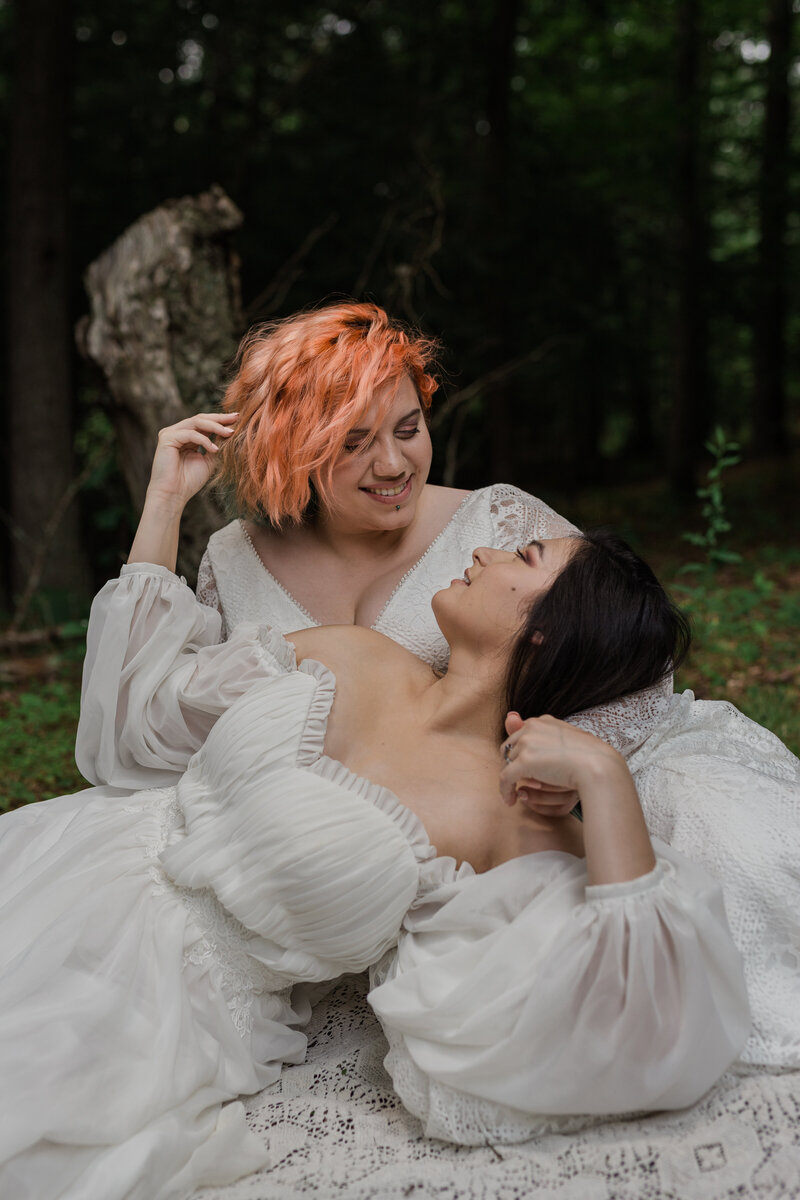 Lesbian couple wearing white dresses looking at each other