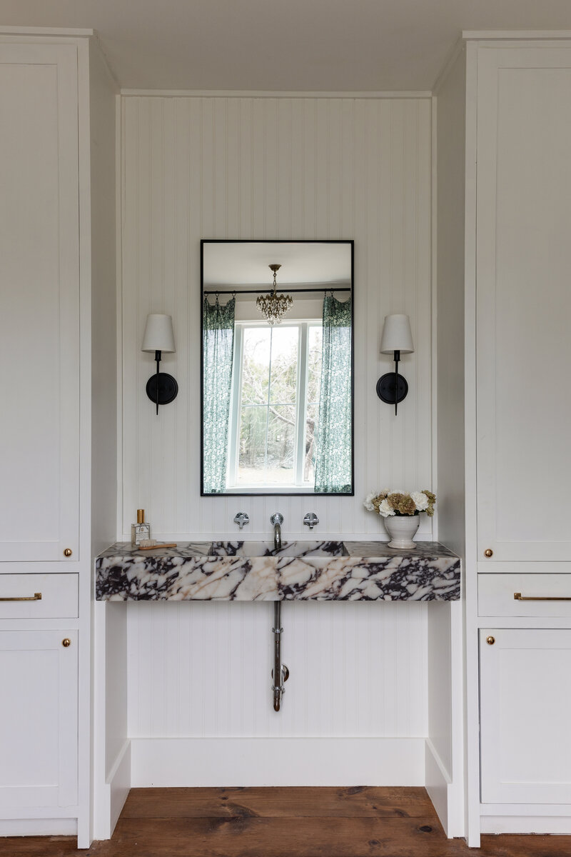 A custom Calacatta Viola sink takes center stage in this primary bathroom designed by Jessa Myer Interiors.