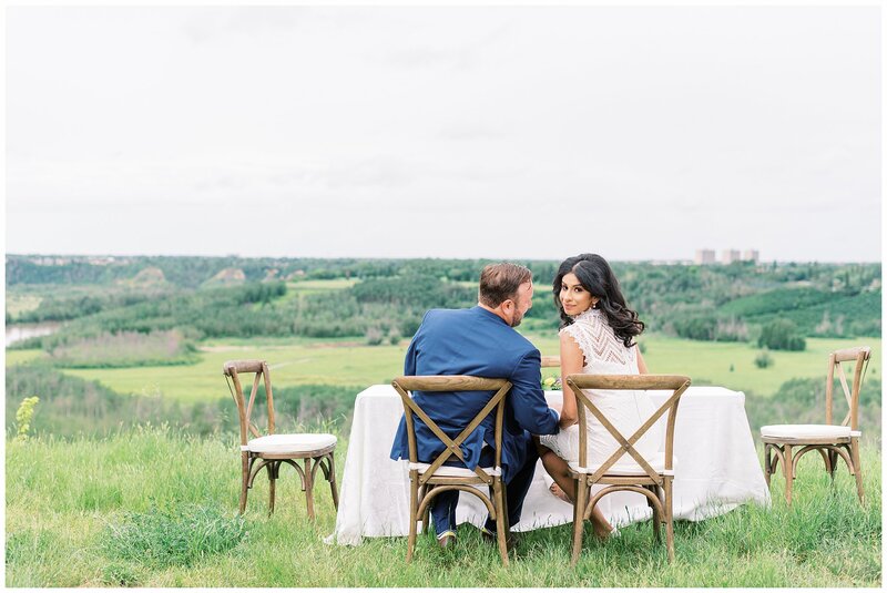 Couple sitting at wedding reception in a lush field