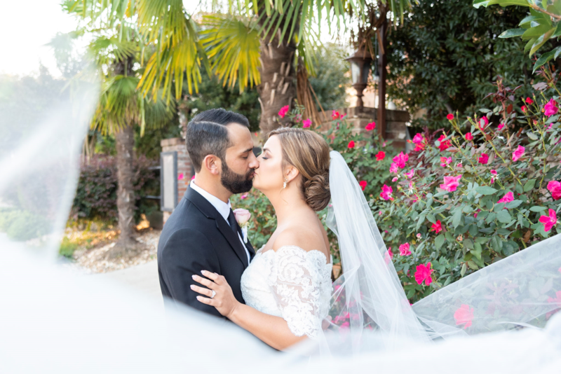 Liz and Brandon share a kiss on their wedding day as husband and wife, with her beautiful viel blowing in the wind