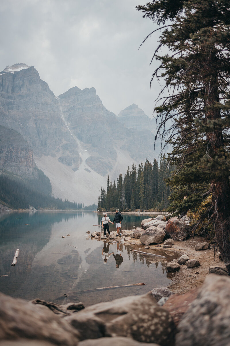Newly-married couple stand together on rocks overlooking the ocean