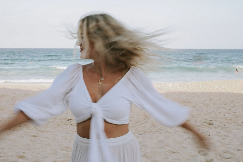 Woman dressed in white running/dancing on the beach 
